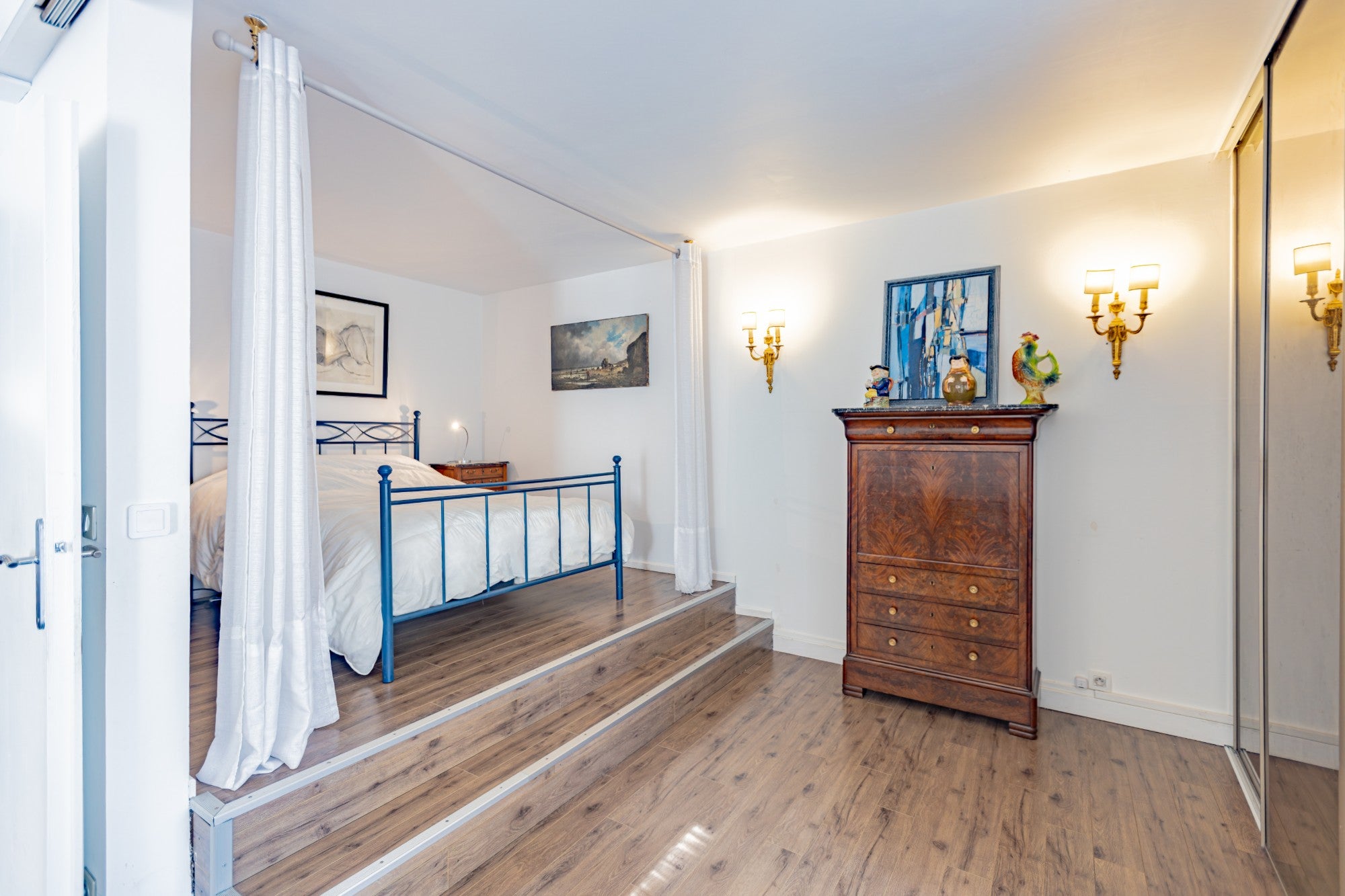 Chambre parentale sur estrade avec lit à baldaquin, commode Louis-Philippe et appliques, photographiée par KEY STUDIO